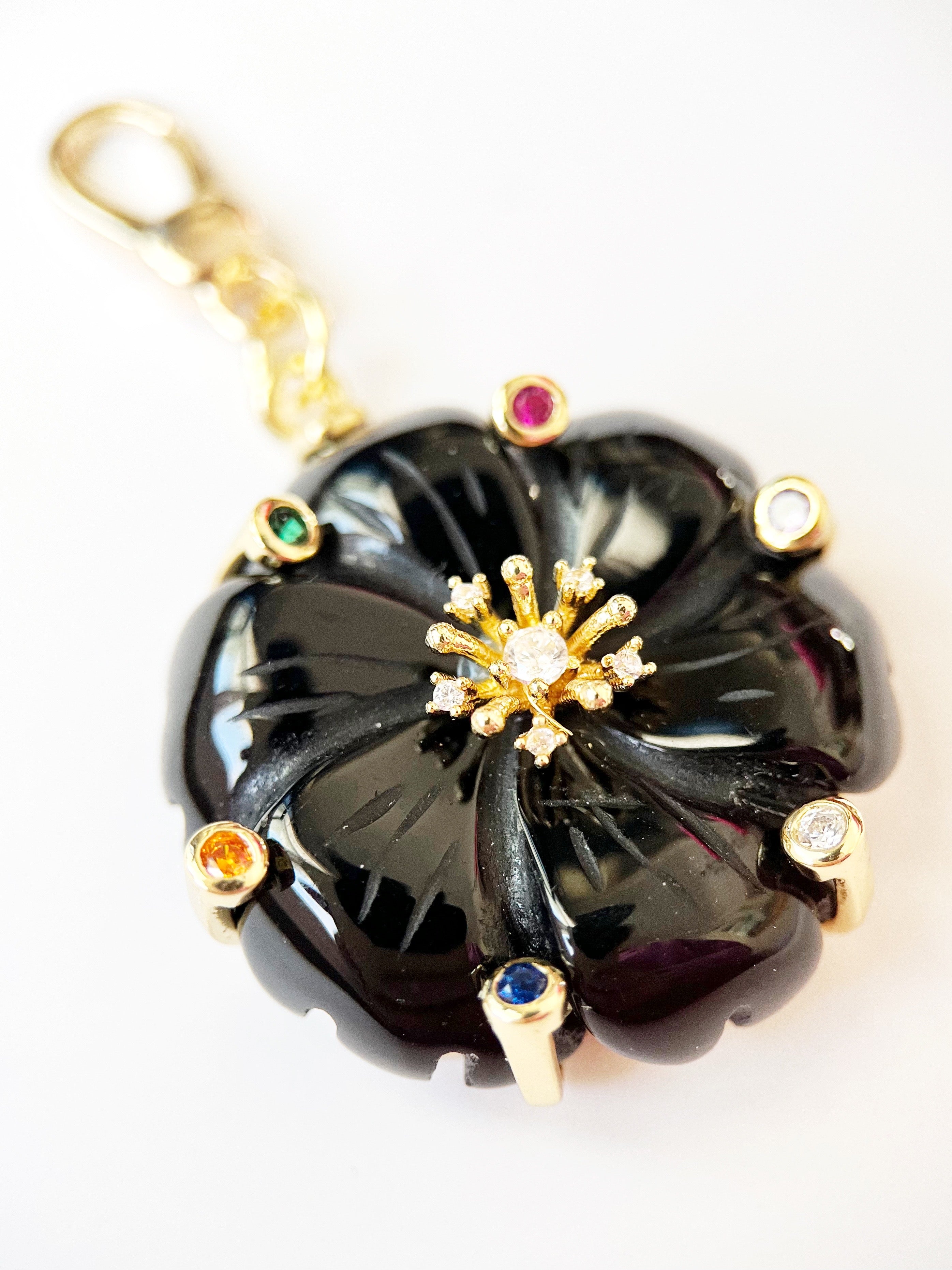 black flower pendant and gold accents on a white background
