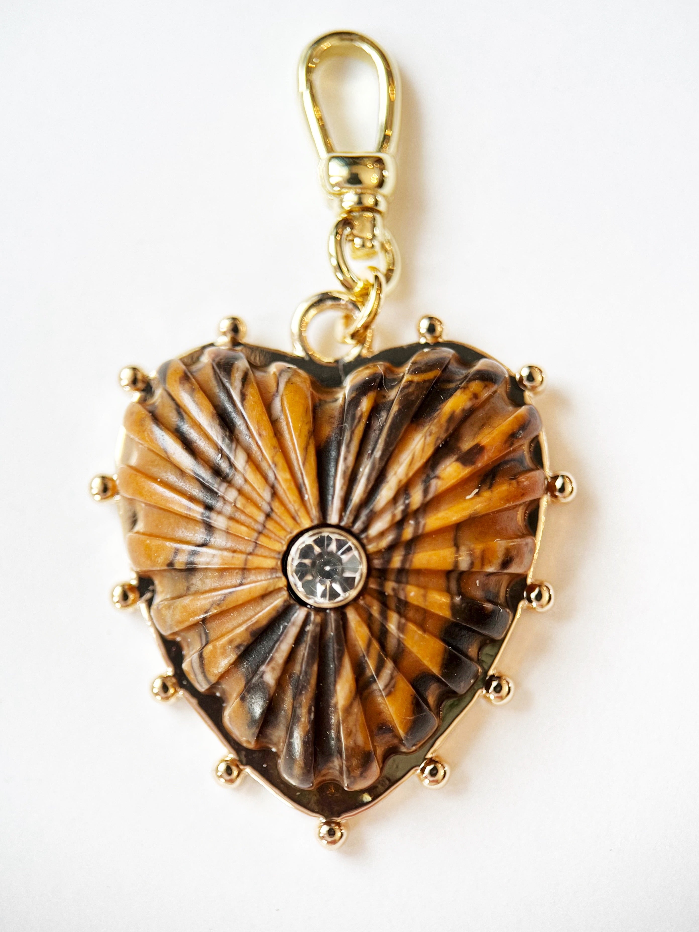 Heart-shaped pendant with tiger's eye pattern and gold accents on a white background
