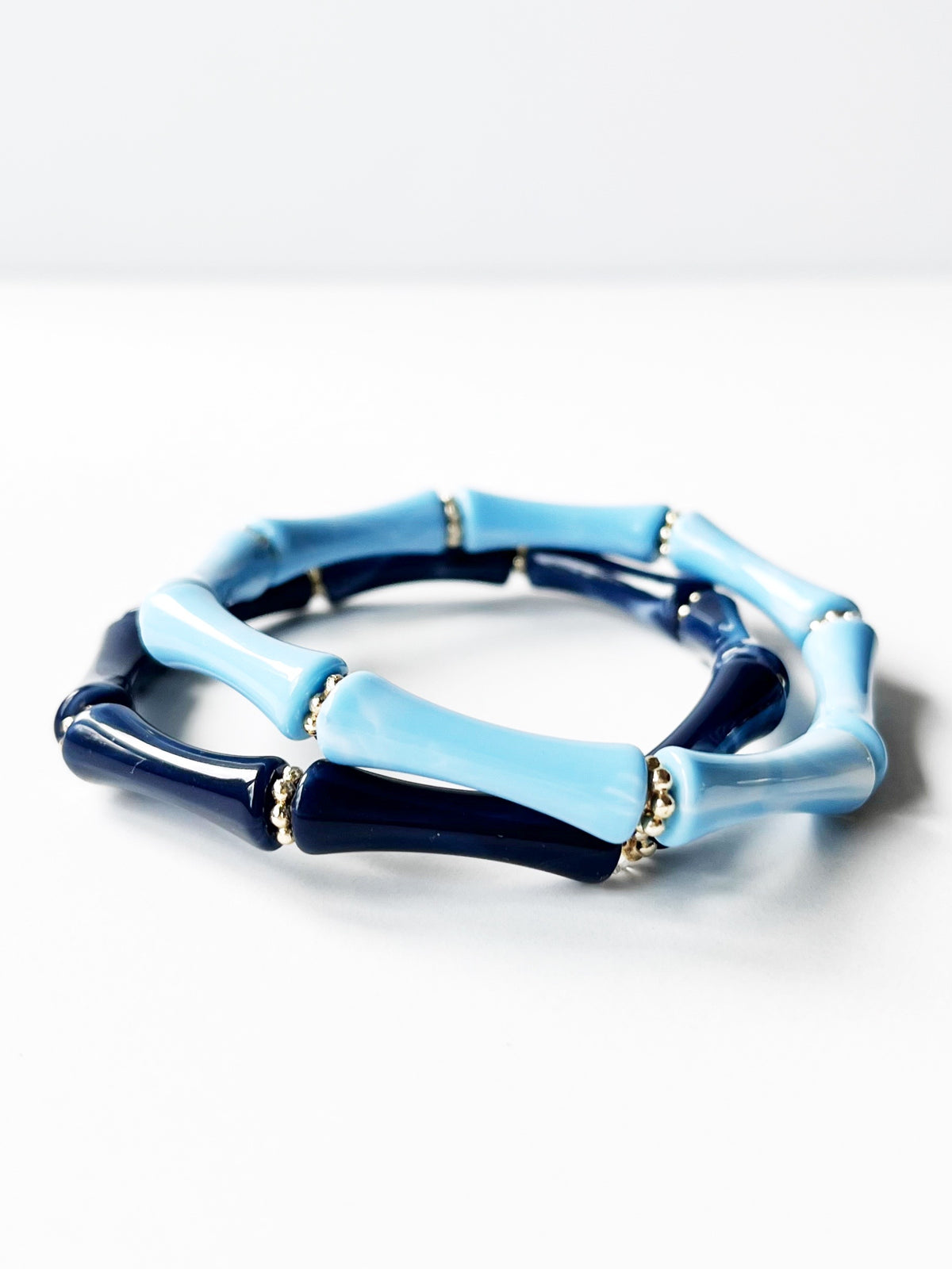 two blue bangle bracelets with gold beads stacked