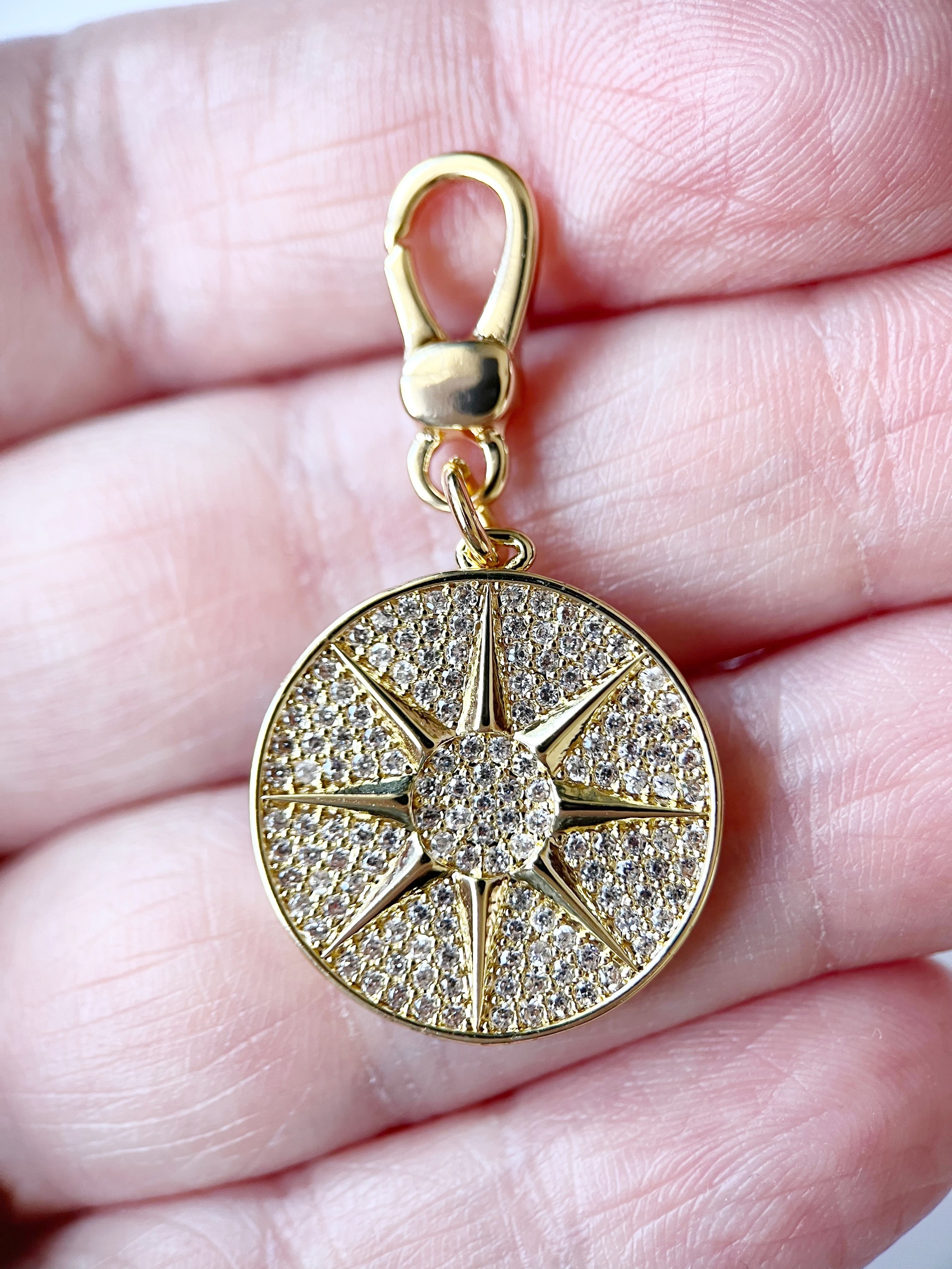 Gold pendant with star design held between fingers