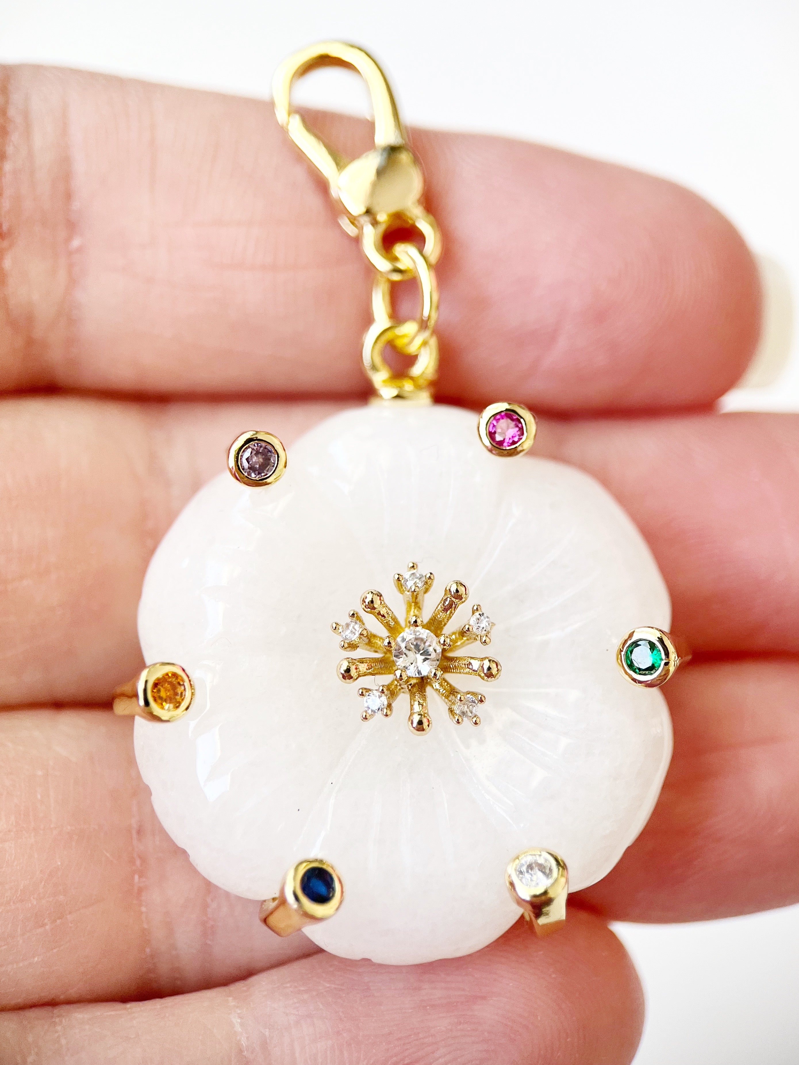 white flower charm with gemstones held in hand