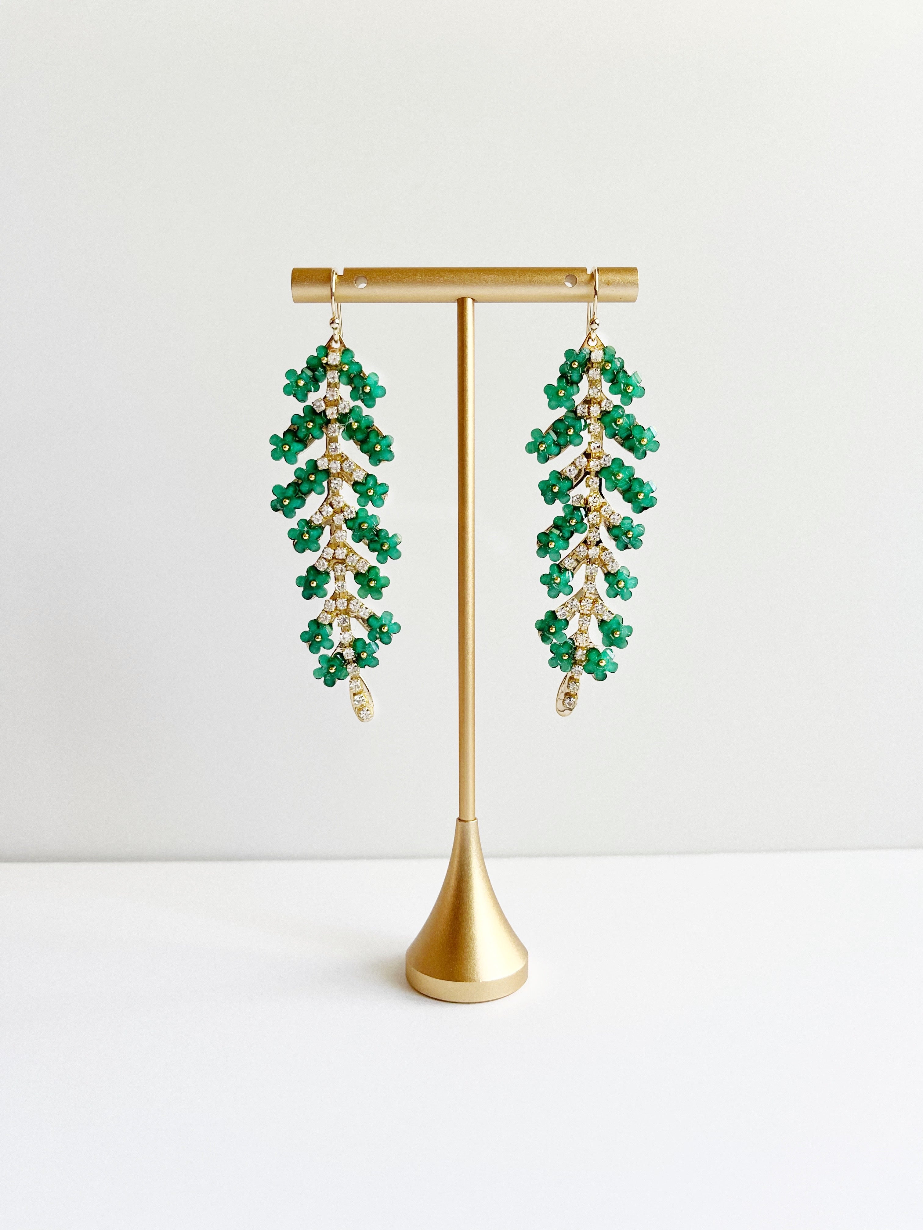 Green Flower Leaf Dangle Statement Earrings displayed on gold earring t stand