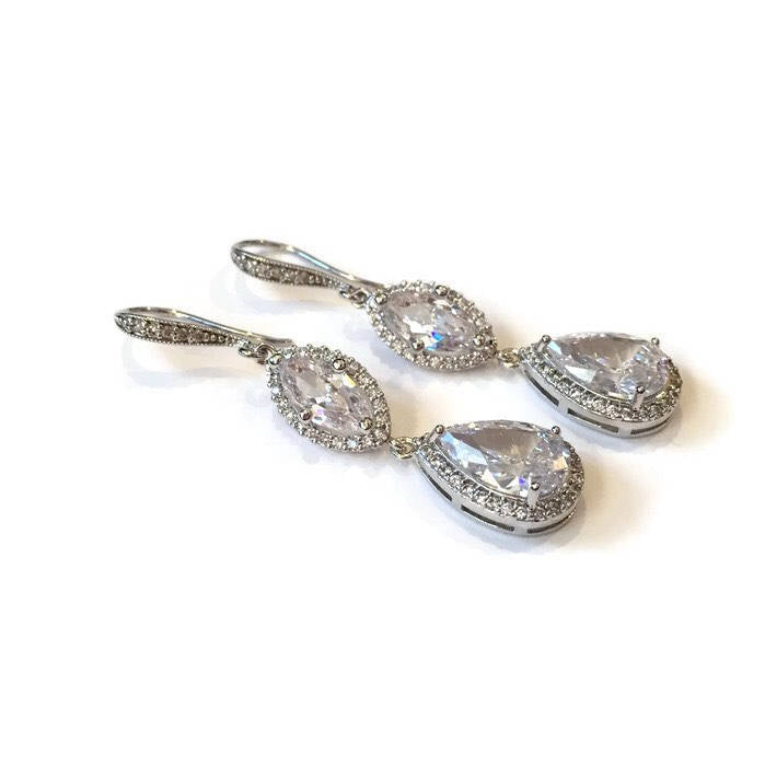 Clear cubic zirconia teardrop crystals in a silver colored rhodium plated brass setting earrings.