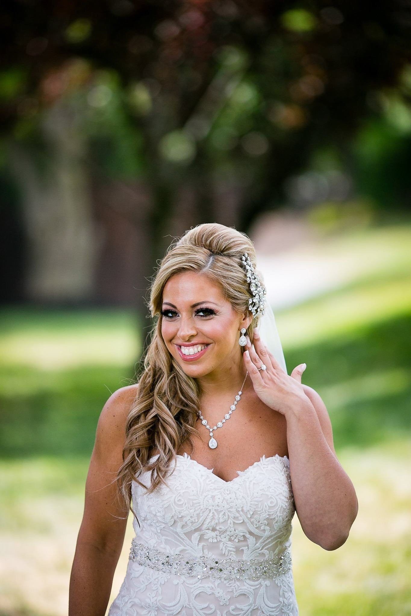 Bride wearing Halo Teardrop cut cubic zirconia crystal with round halo accent set in silver color rhodium plated brass earrings.