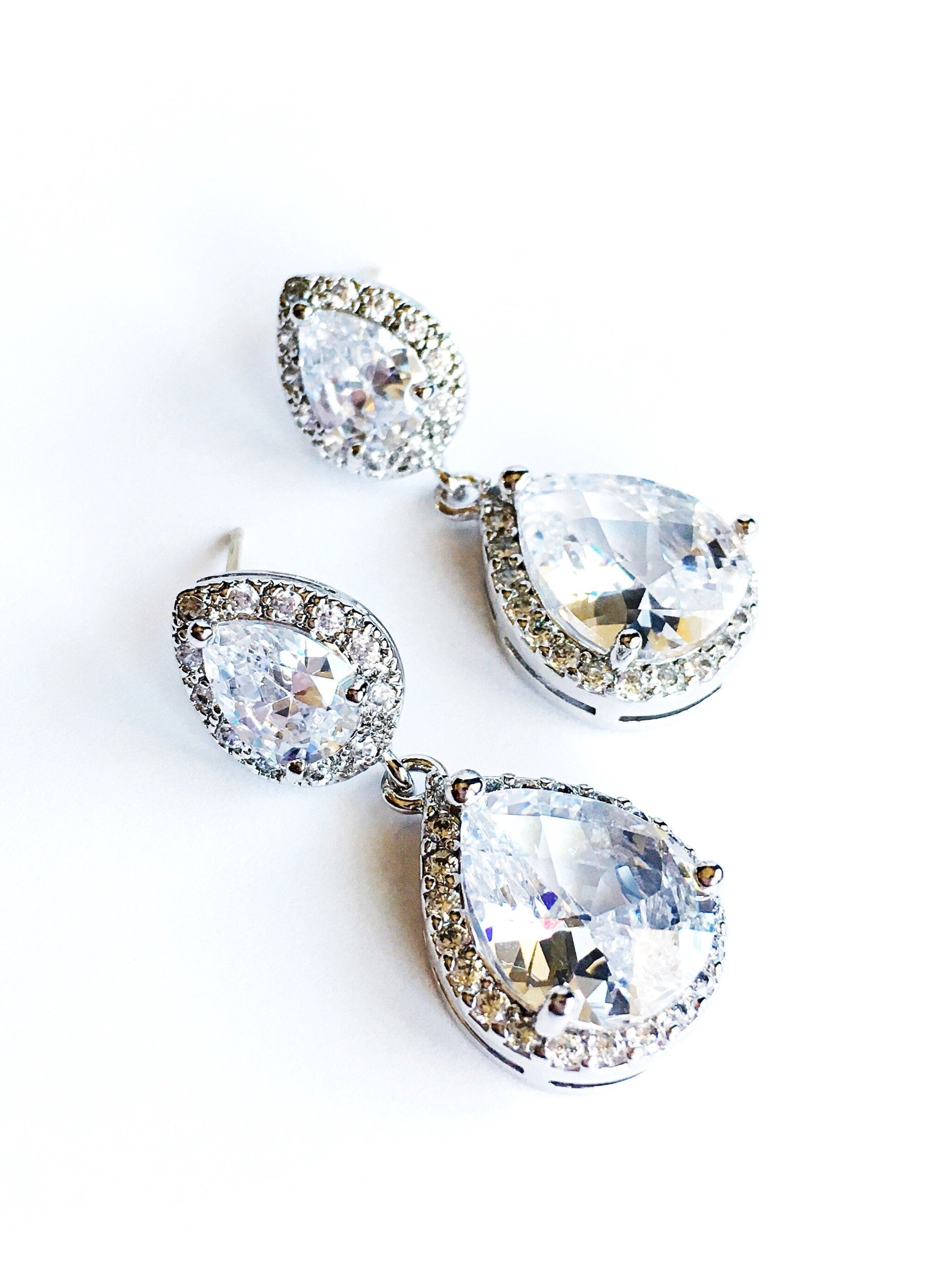 Clear cubic zirconia teardrop crystals in a silver colored rhodium plated brass setting earrings.