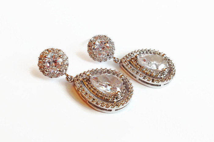 Halo Teardrop cut cubic zirconia crystal with round halo accent set in silver color rhodium plated brass earrings.