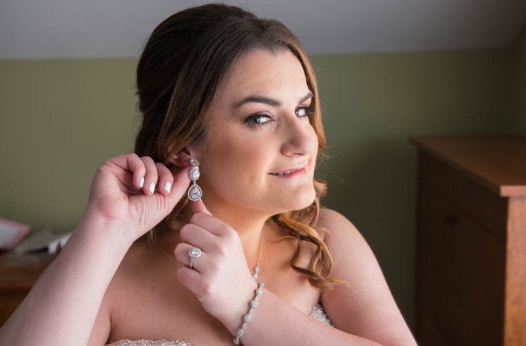 Bride wearing Cubic zirconia teardrop crystals in a silver colored rhodium plated brass setting statement chandelier earrings.
