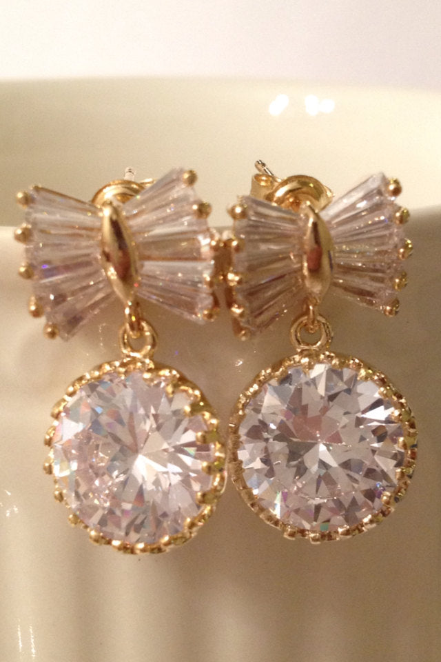 Close up of Gold Bow Bridal Drop Earrings with Cubic zirconia teardrop crystals in a yellow gold colored rhodium plated brass setting.