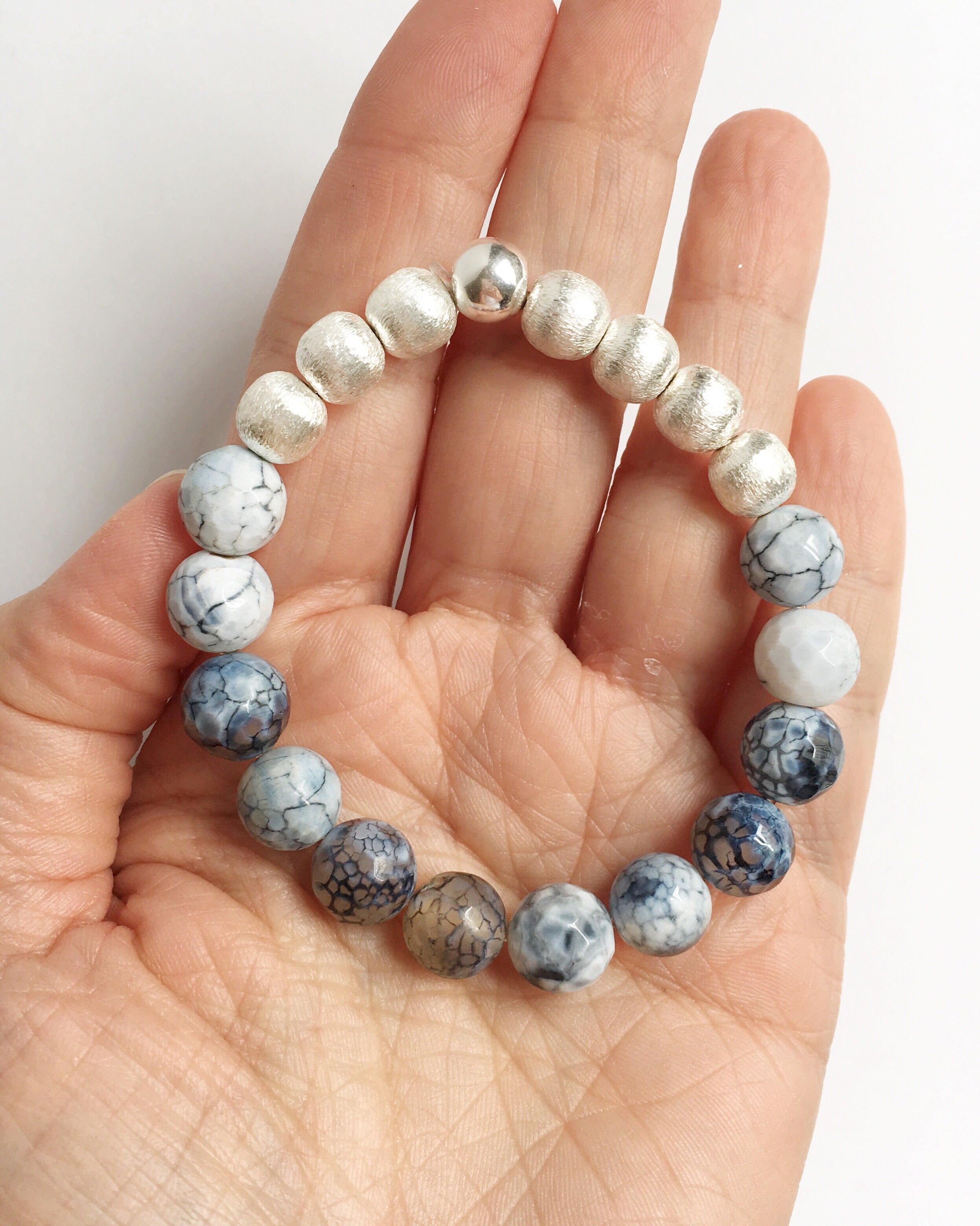 Hand, Palm up, holding Black Lace Agate and Silver Stacking Beaded Stretch Bracelet