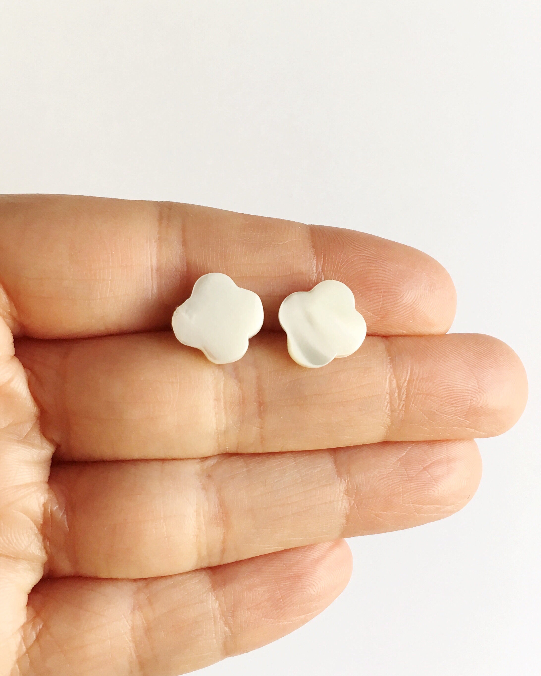 Mother of Pearl Clover Stud Earrings held between fingers