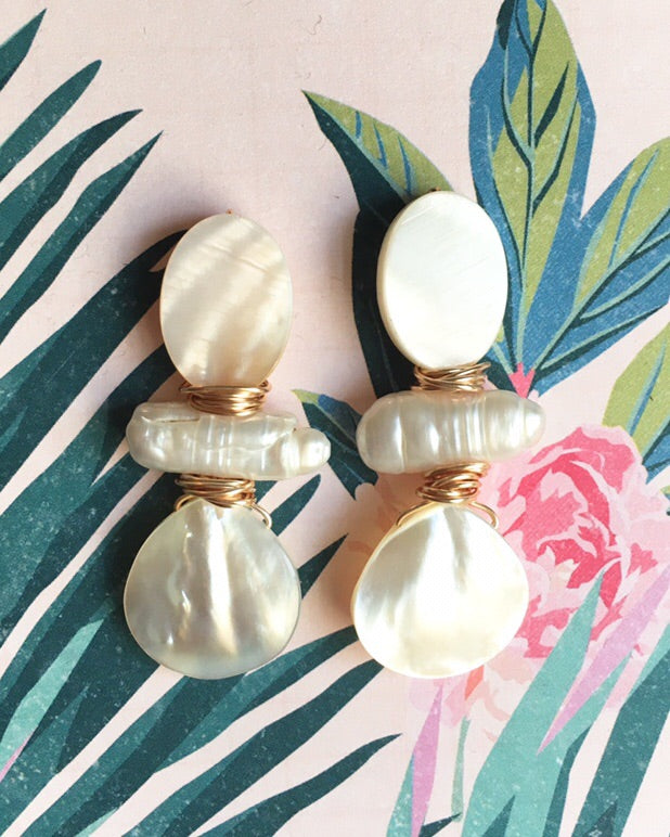 Three Stone Mother of Pearl and pearl stone earrings wrapped with gold plated wire on a pink and floral background.