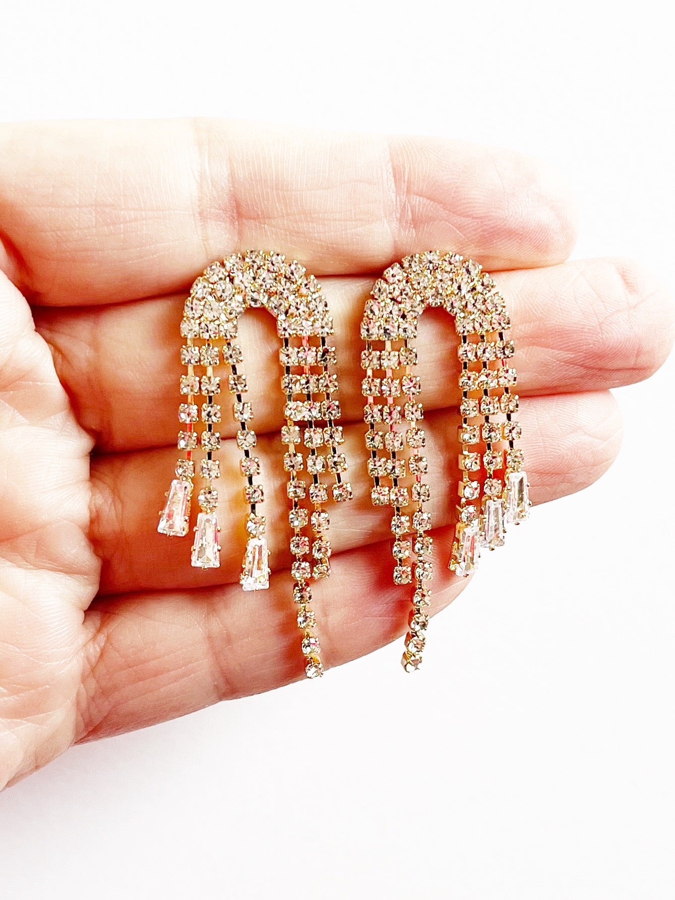 statement gold earrings with crystals displayed on hand