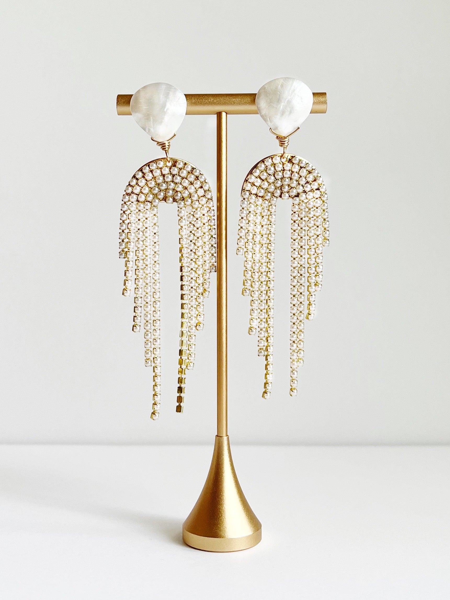 Pearl drop earrings displayed on gold earring tstand