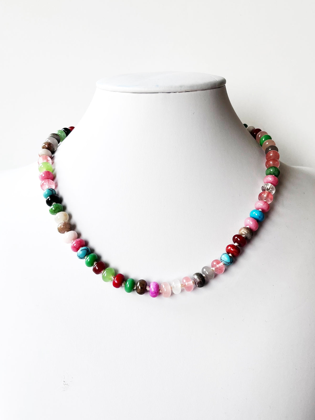 A colorful beaded necklace displayed on a white mannequin
