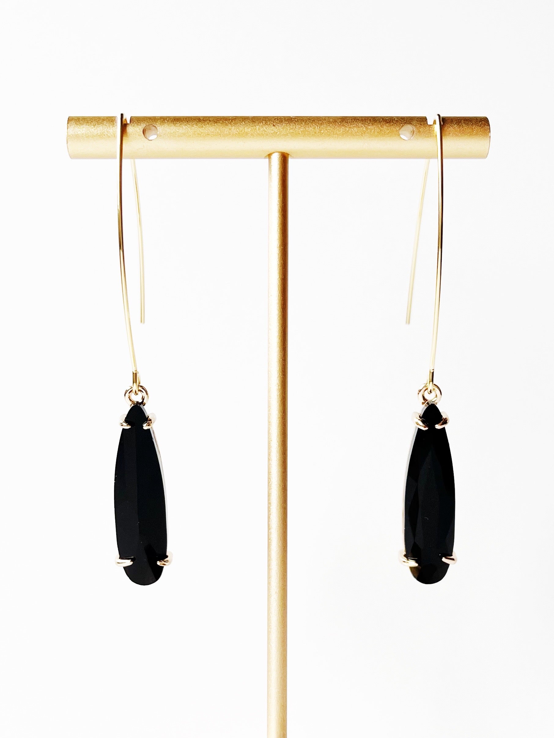 black pendant earrings on gold stand