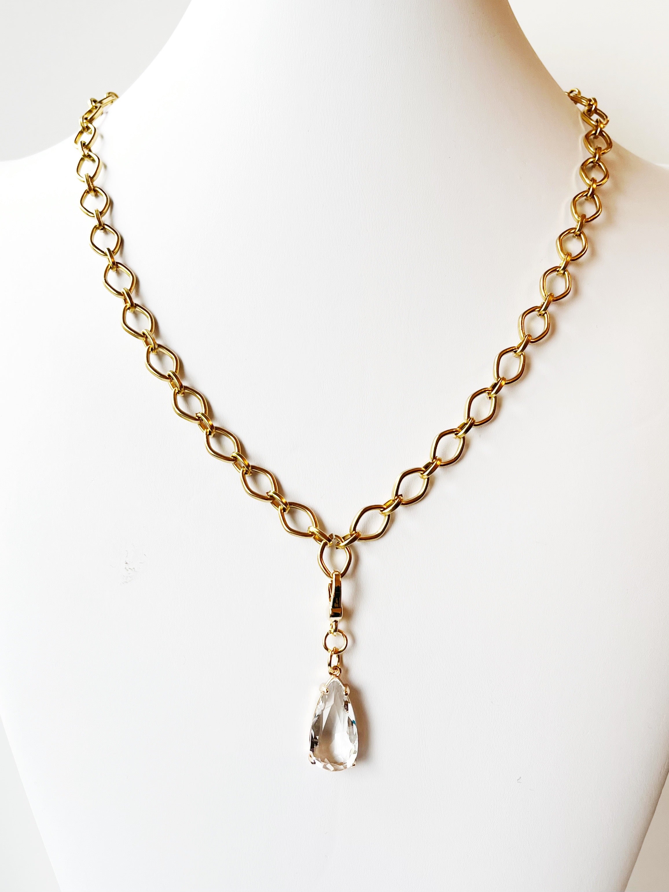 Gold chain necklace with a teardrop pendant on a mannequin against a white background