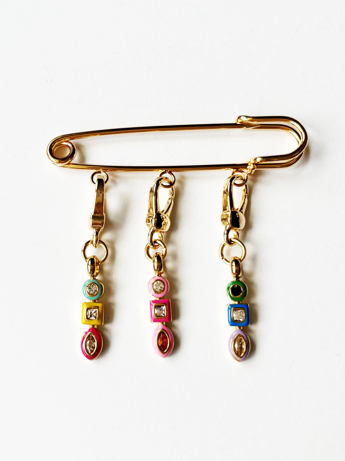 Gold brooch with colorful dangling charms on a white background