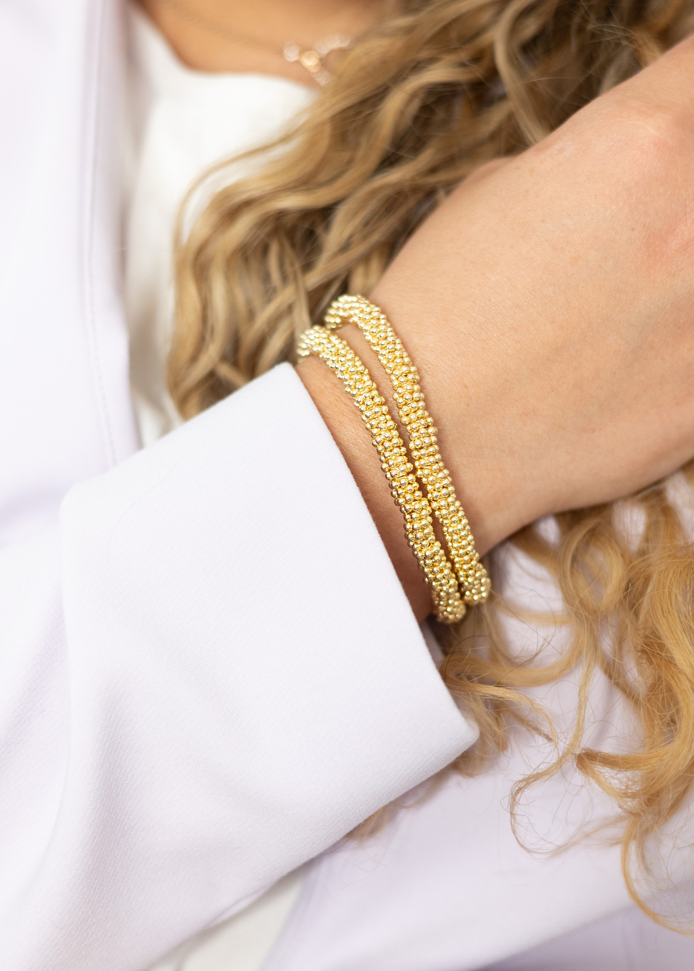 gold stacked bracelets on hand