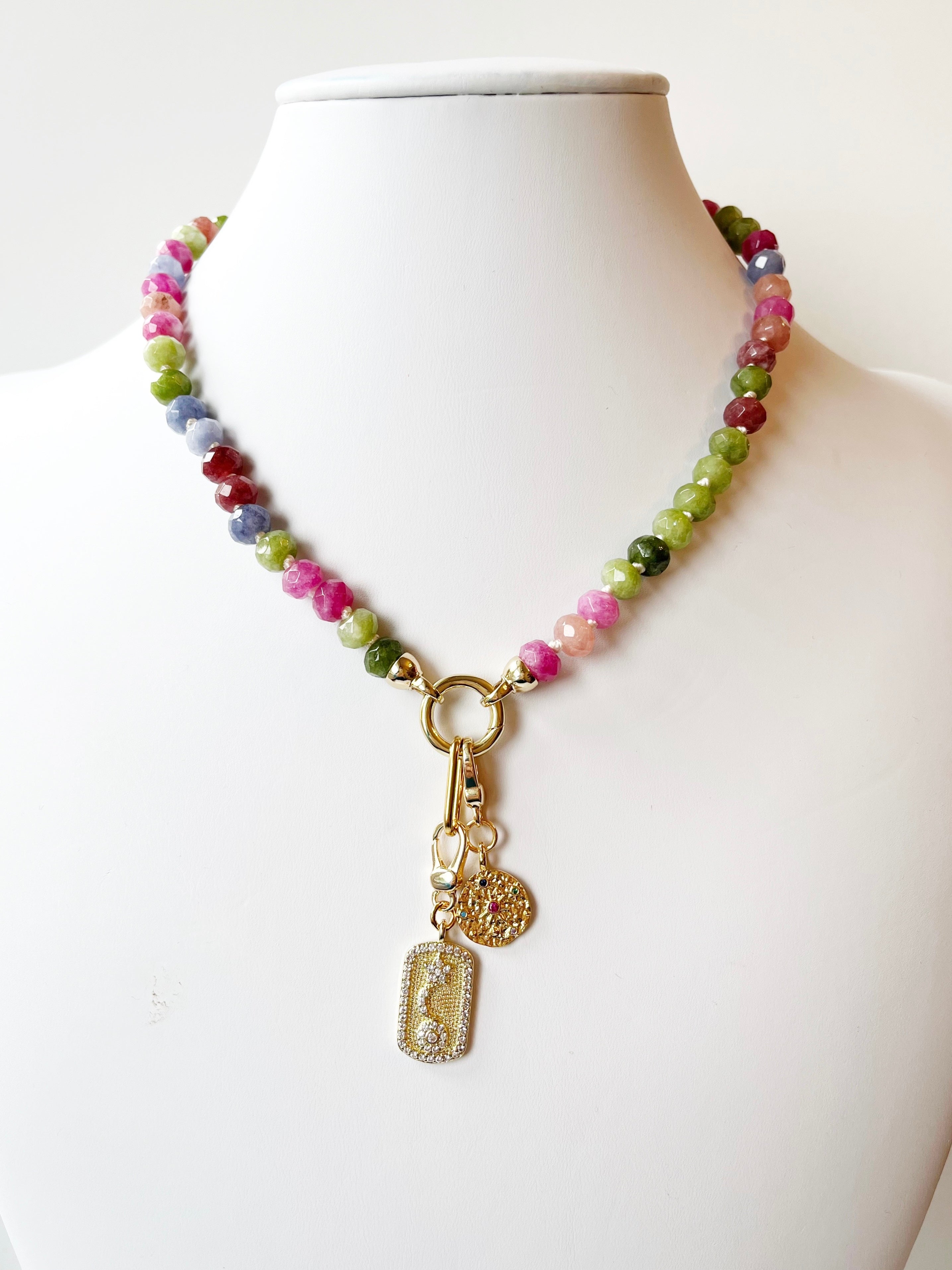 Necklace with multicolored beads and gold charm on a mannequin against a white background
