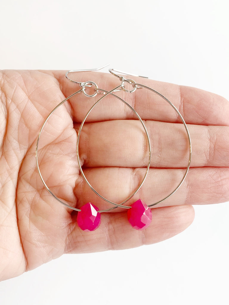 silver statement earrings with pink accent displayed on hand