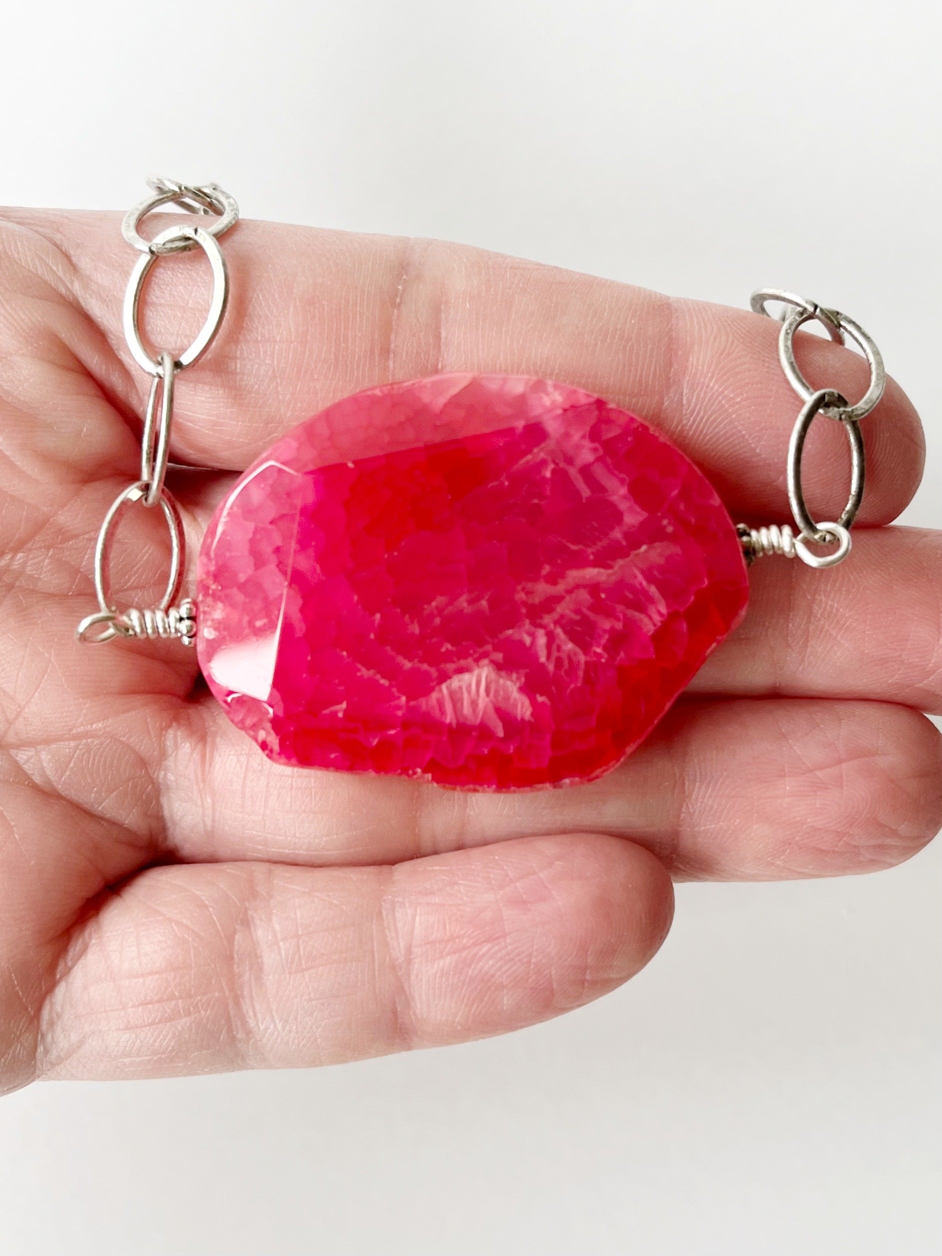 pink agate pendant necklace displayed on hand