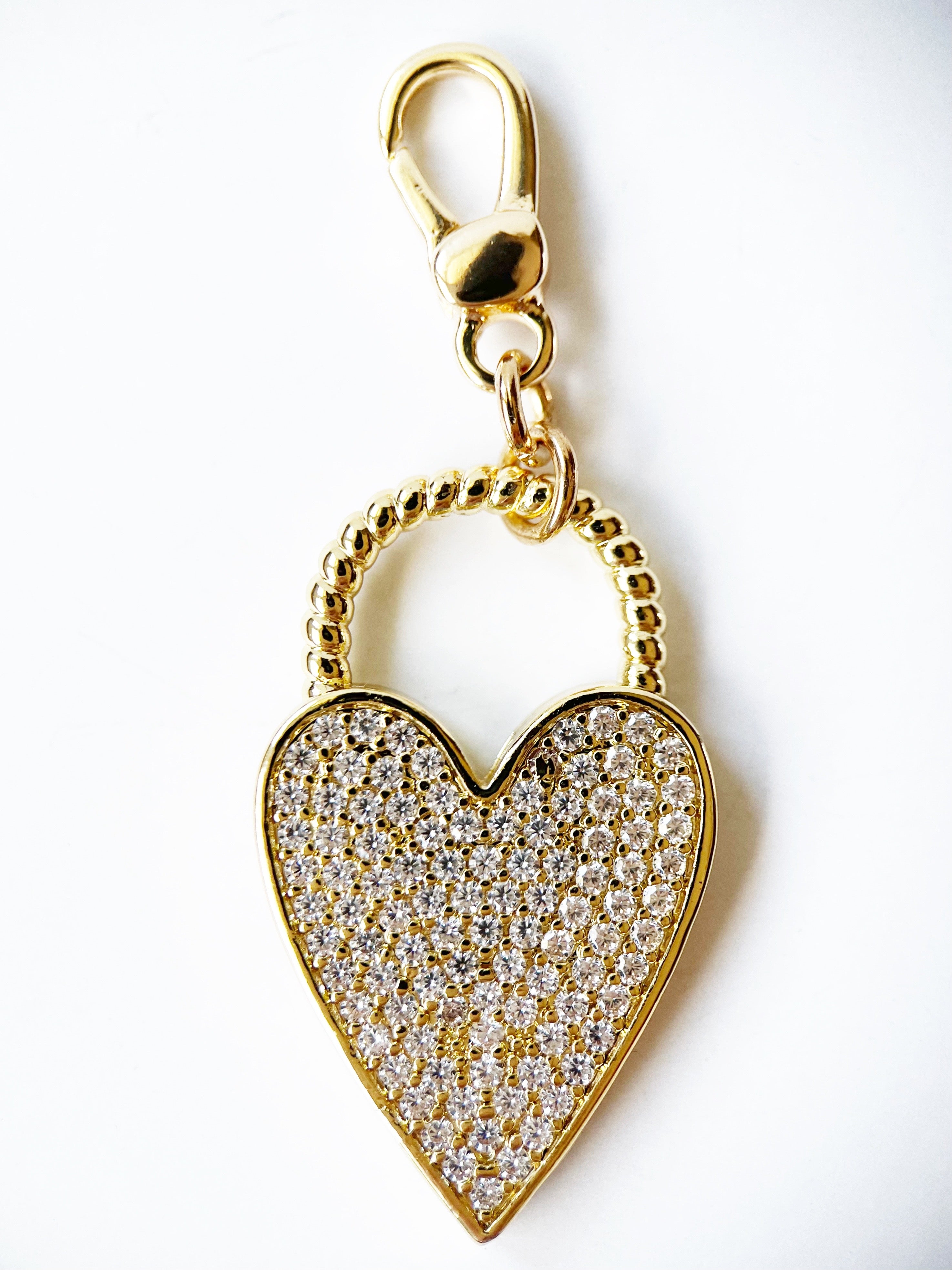 Gold heart-shaped pendant with clear stones on a white background