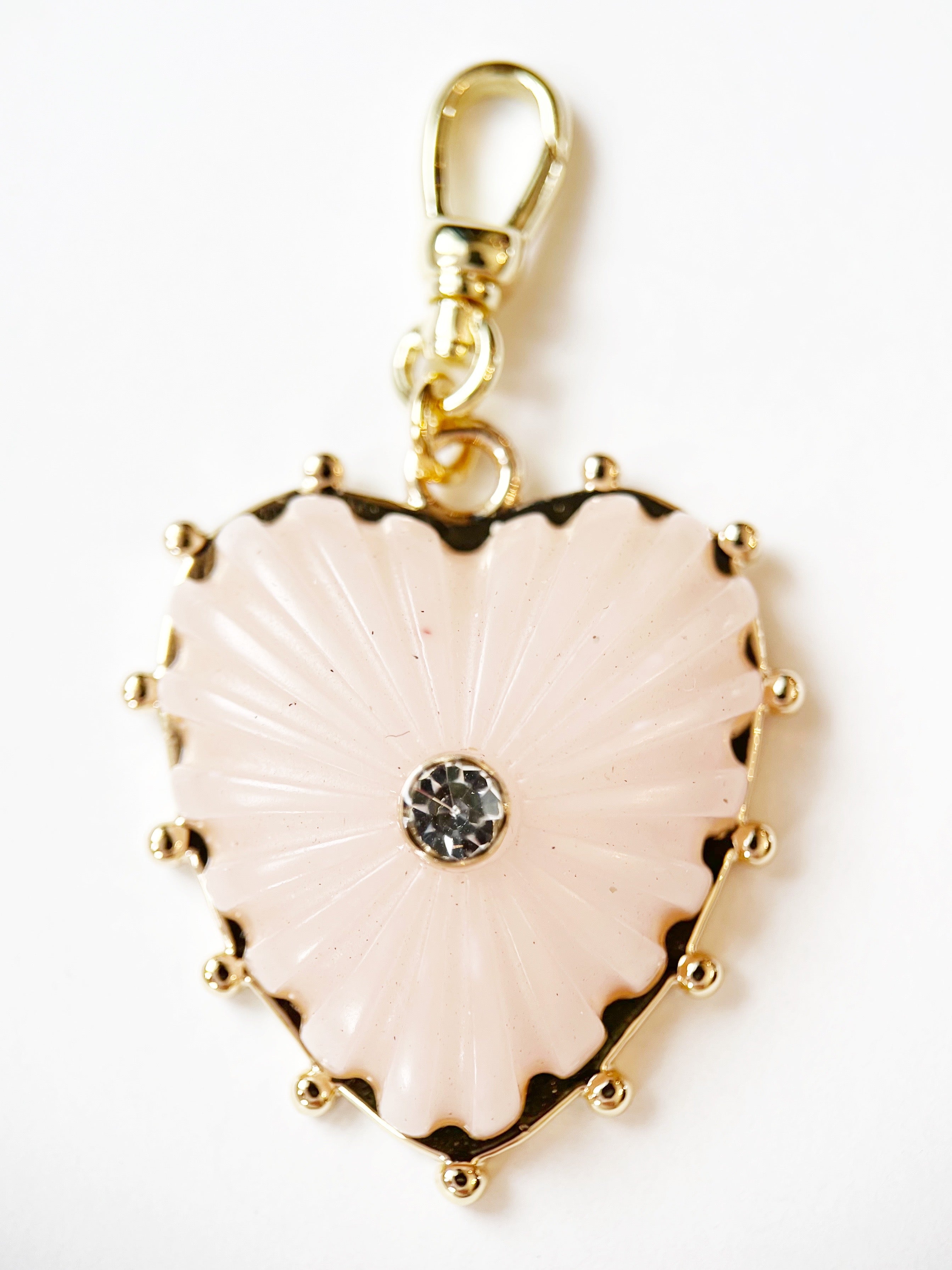 Heart-shaped pendant with gold border and central gemstone on a white background