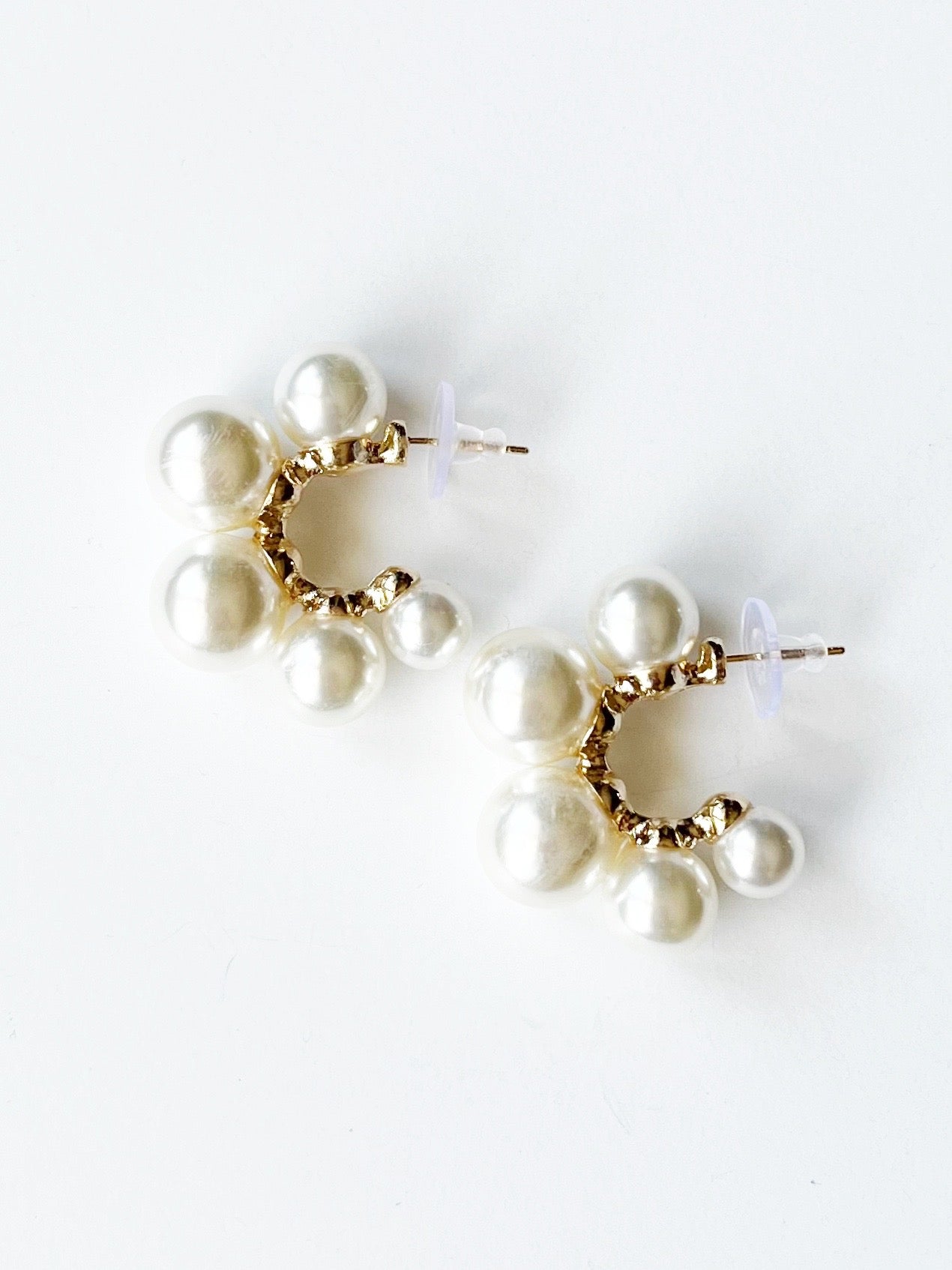 Pair of pearl earrings with gold circular centers on a white background
