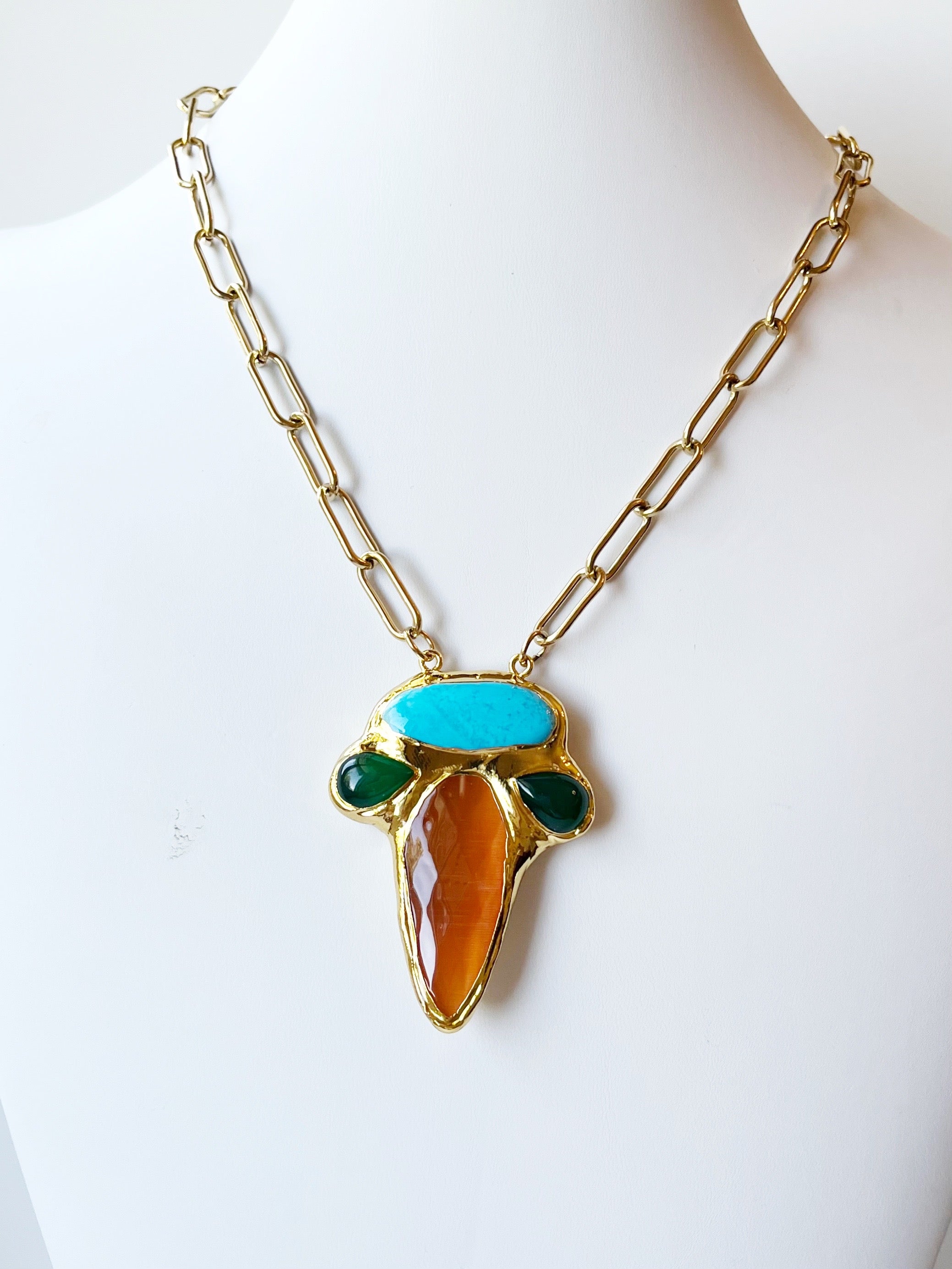 Necklace with gold chain and colorful pendant on a mannequin
