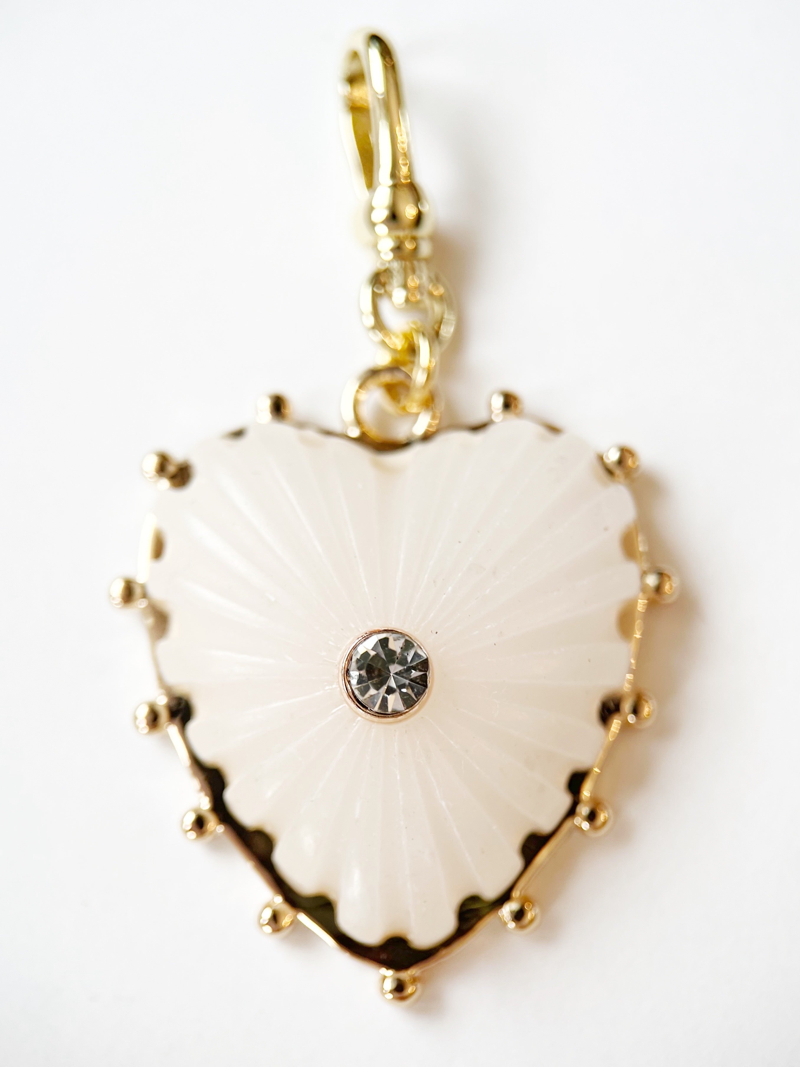 Heart-shaped pendant with gold border and central gemstone on a white background