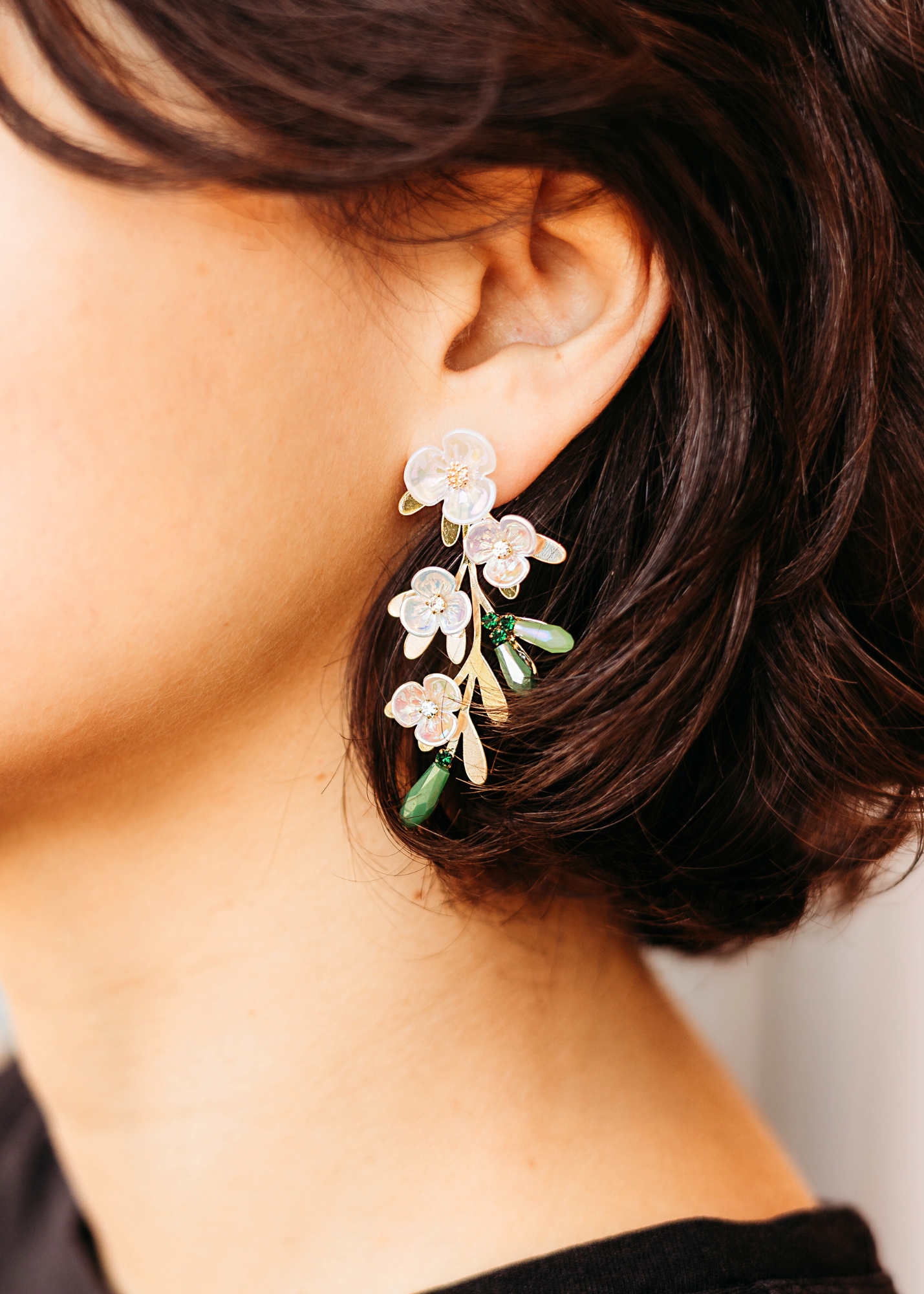 Close-up of a person wearing floral earrings with a blurred background