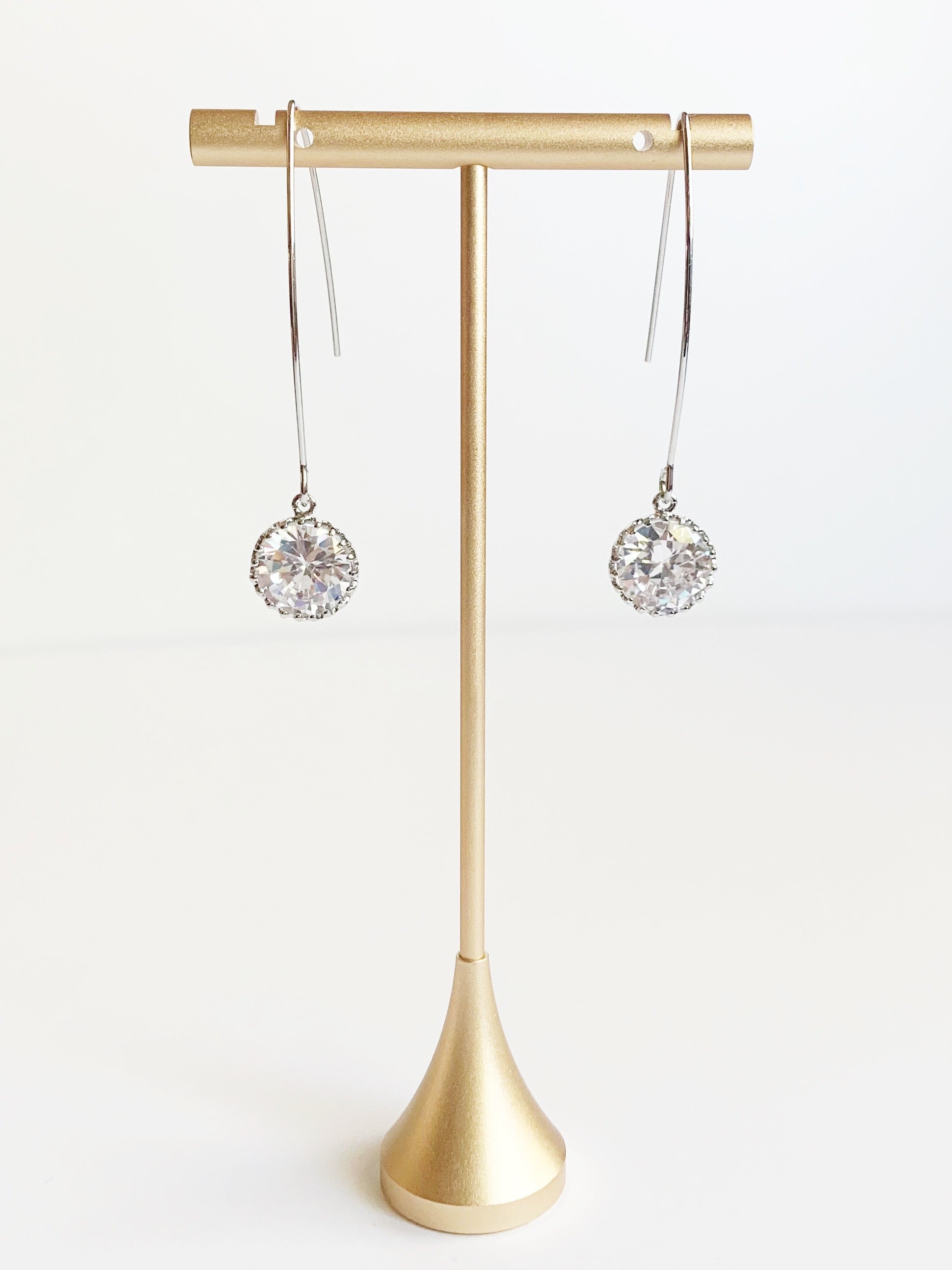 long silver earrings with crystals on gold earring tstand