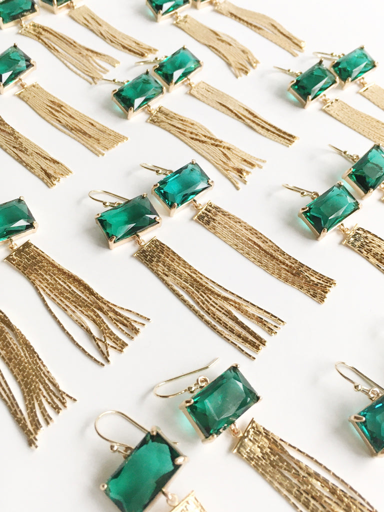 Emerald Green and Gold Tassel Dangle Earrings scattered on the table.