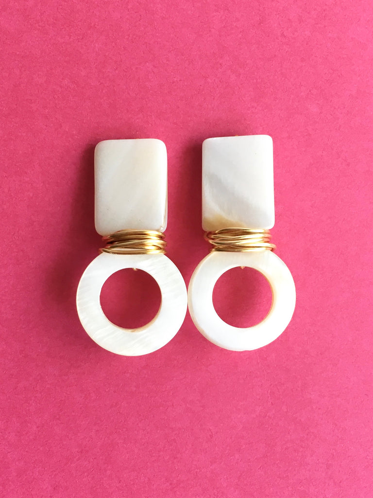 Rectangle pearl stud with round pearl shell earrings with wrapped gold plated wire on pink background.