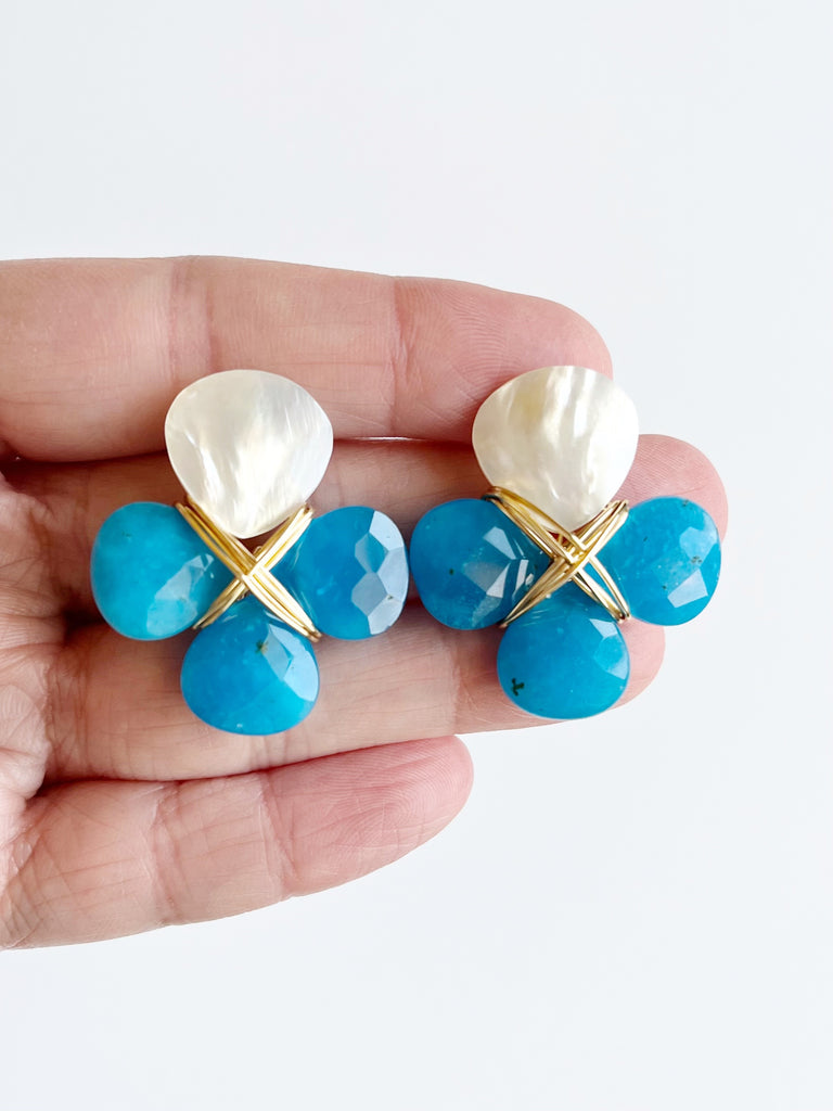 blue quartz and mother of pearl earrings wrapped with gold wire displayed on hand