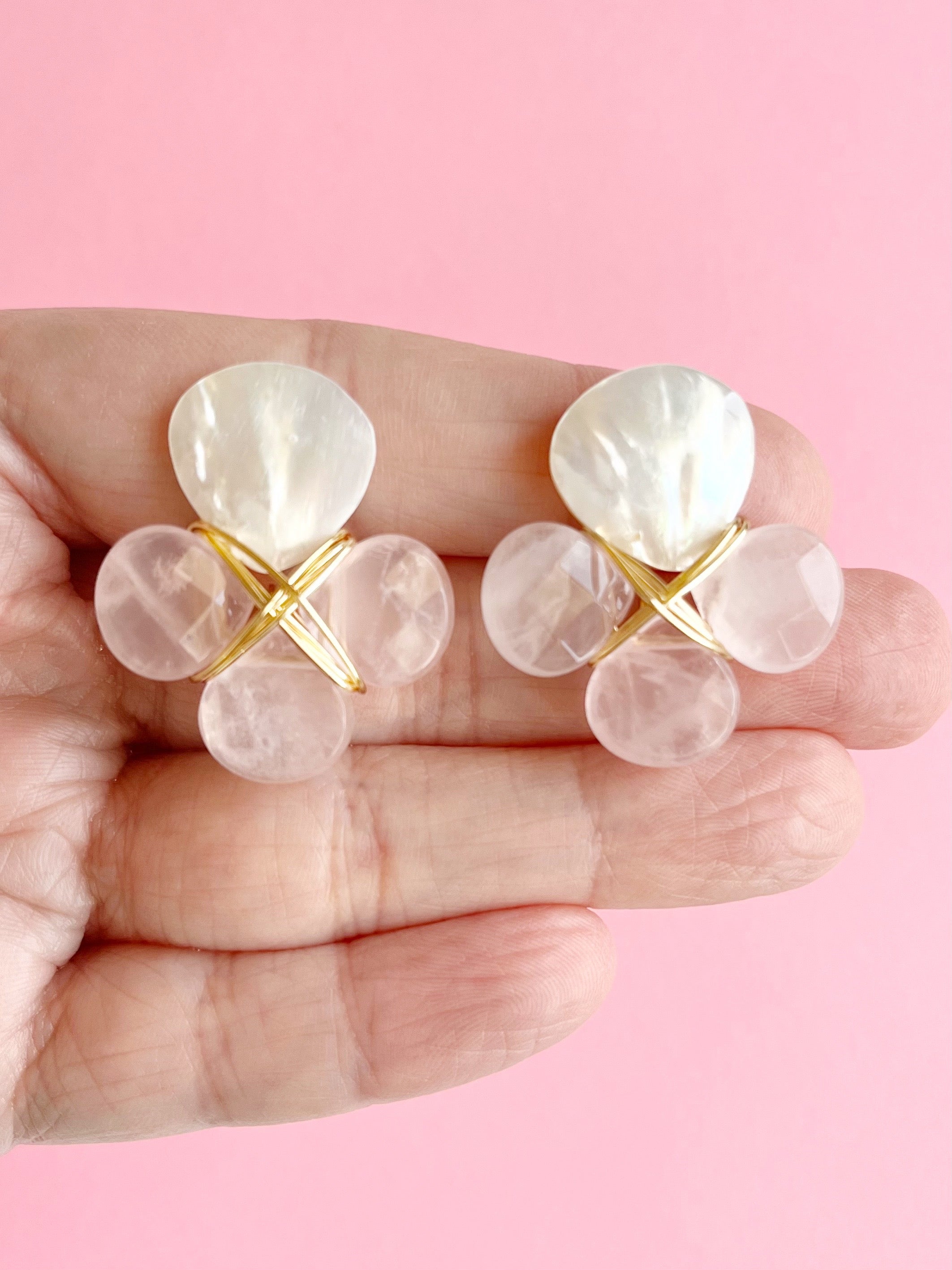rose quartz and mother of pearl earrings wrapped in gold wire displayed on hand