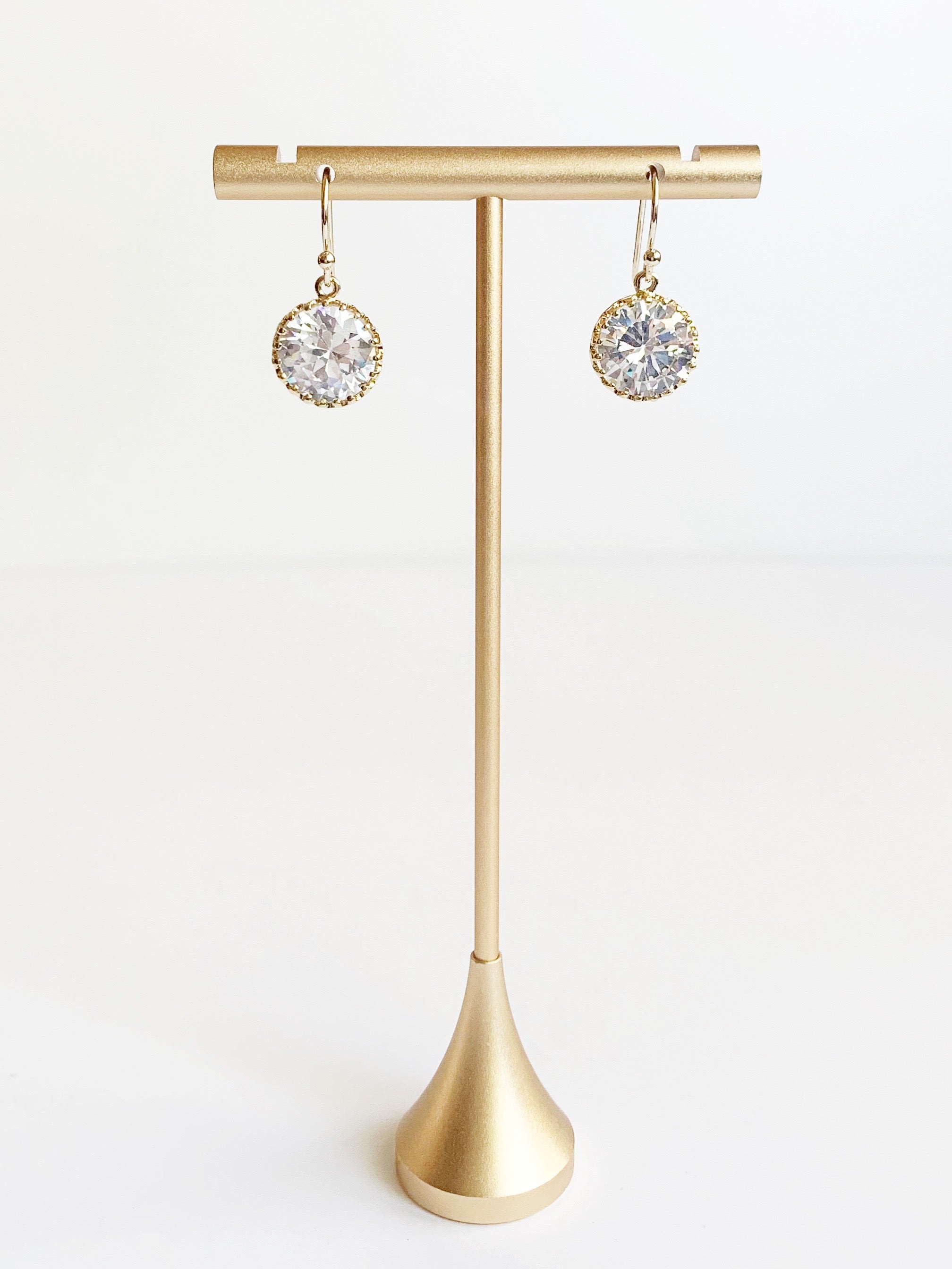 crystal dangle earrings in gold displayed on earring stand