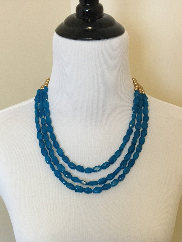 Mannequin wearing Three strand turquoise quartz and gold wooden beaded necklace close up.
