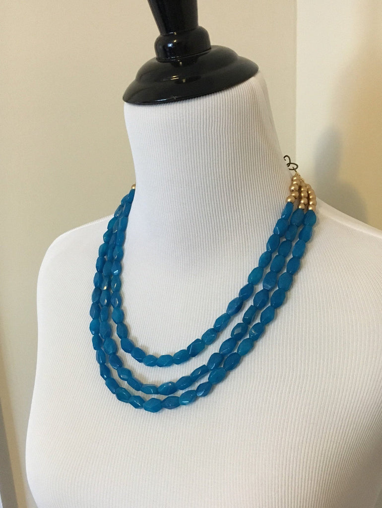 Side view of Mannequin wearing Three strand turquoise quartz and gold wooden beaded necklace. 