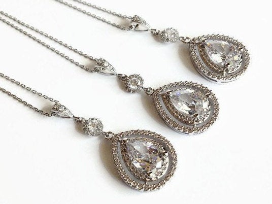 Teardrop cut cubic zirconia crystal with round halo accent set in silver color rhodium plated brass pendant necklace.