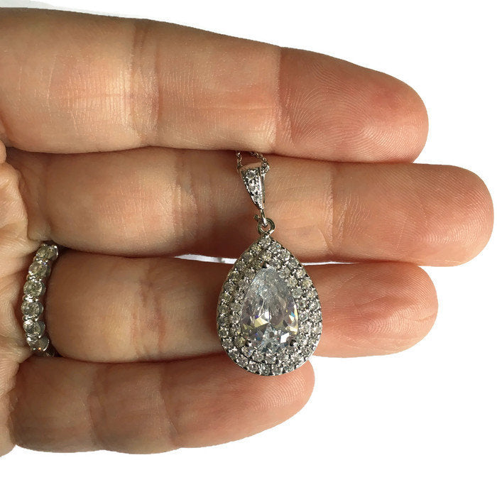 Hand holding Double halo Teardrop cut cubic zirconia crystals set in silver color rhodium plated brass pendant necklace