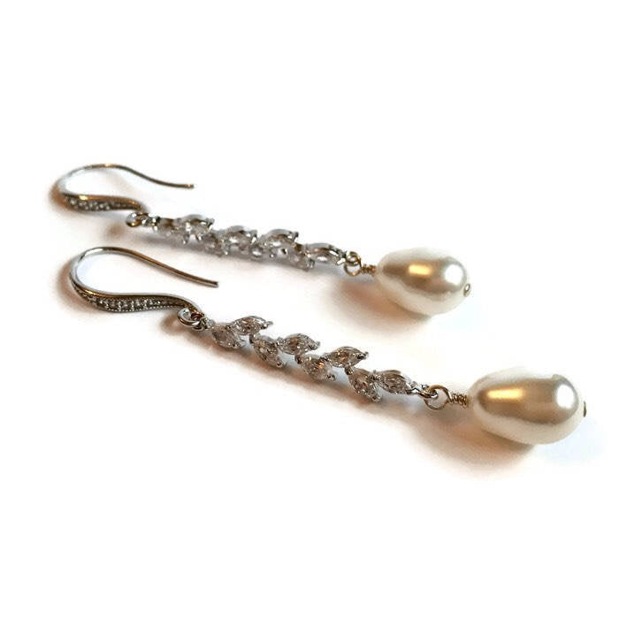 Glass pearl earrings accented by clear cubic zirconia crystals in a silver colored rhodium plated brass setting
