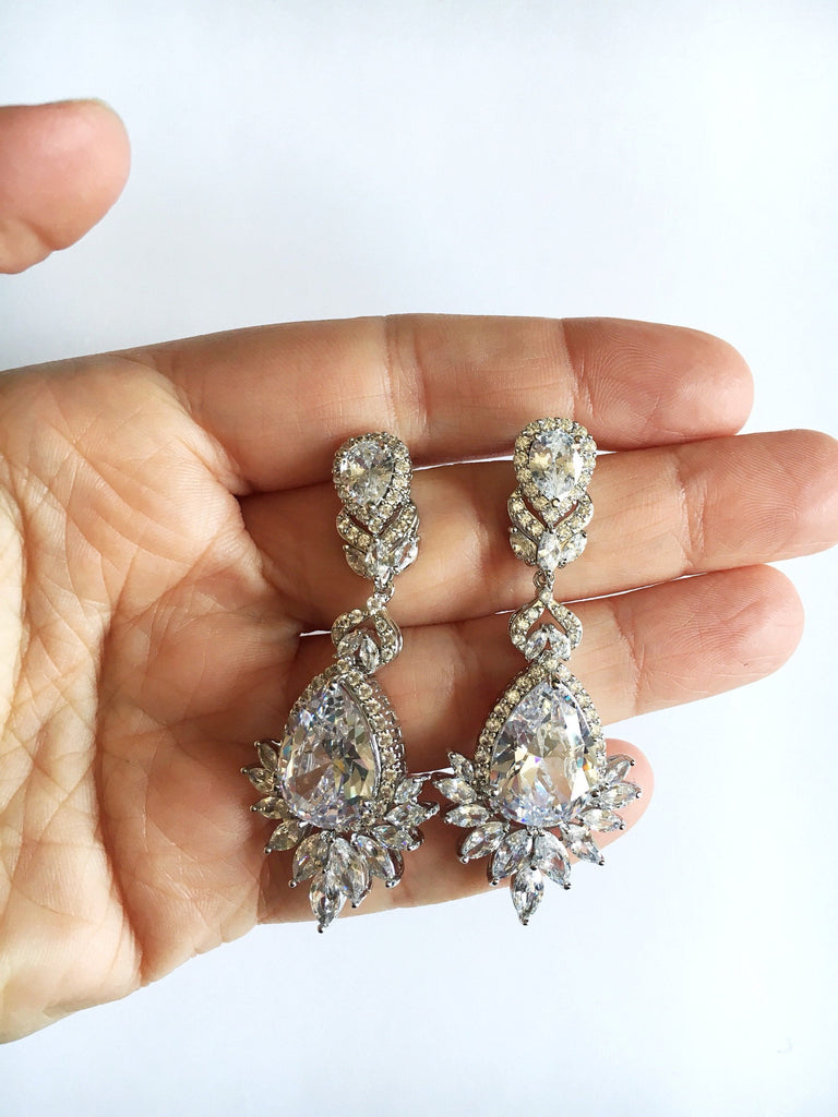 Hand holding Crystal Cubic zirconia and silver drop earrings. 