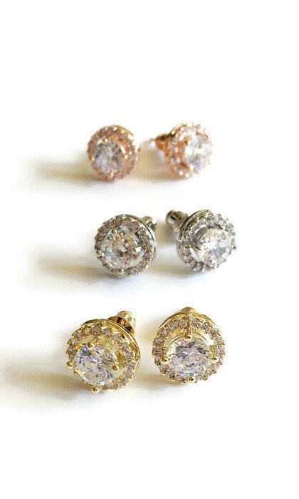 Round cubic zirconia halo stud earrings in a silver colored rhodium plated brass setting also in a gold plated and rose gold plated setting.