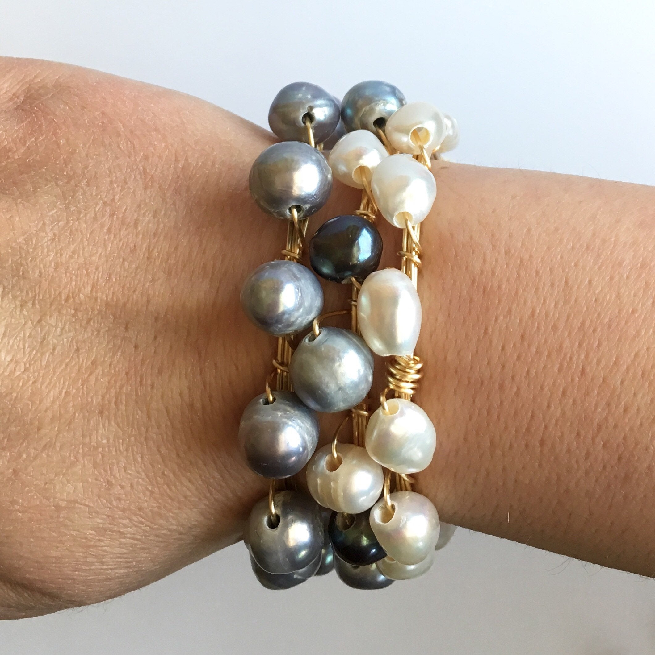 Three Pearl and Gold Bangle Bracelet on women's wrist.