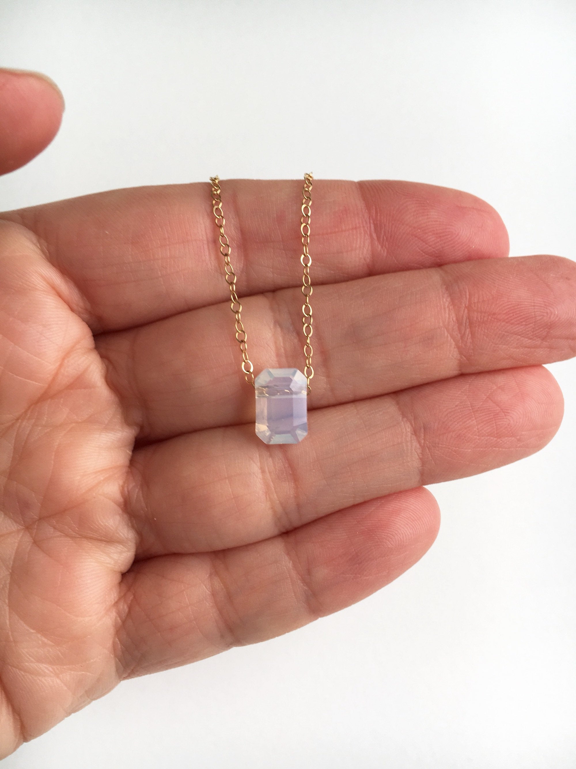 white opal octagon pendant on gold chain displayed on hand