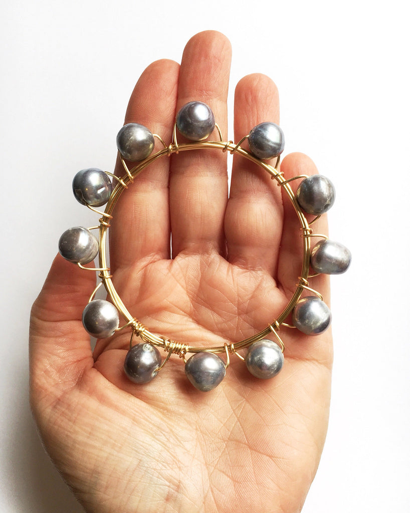 Pearl and Gold Bangle Bracelet held in hand.