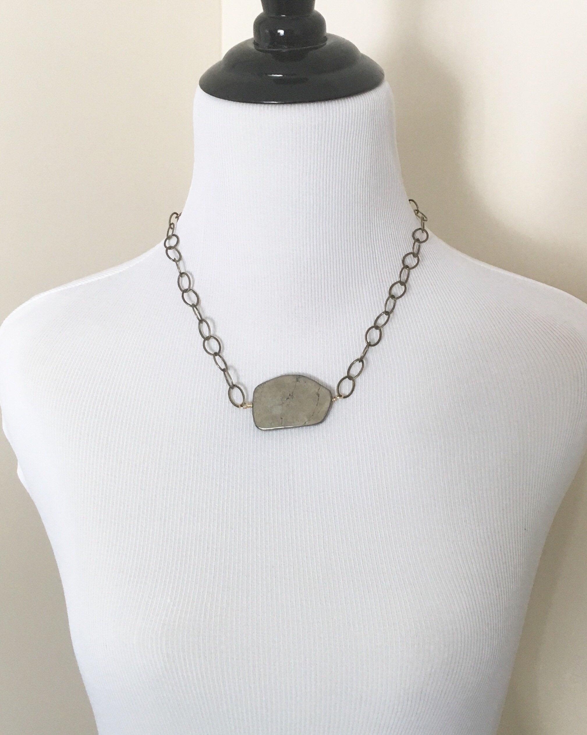 Mannequin wearing Sliced pyrite stone hand wired onto yellow gold antique brass plated chain necklace.