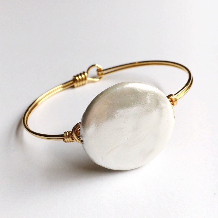 Hand wired gold bangle bracelet with white backing..