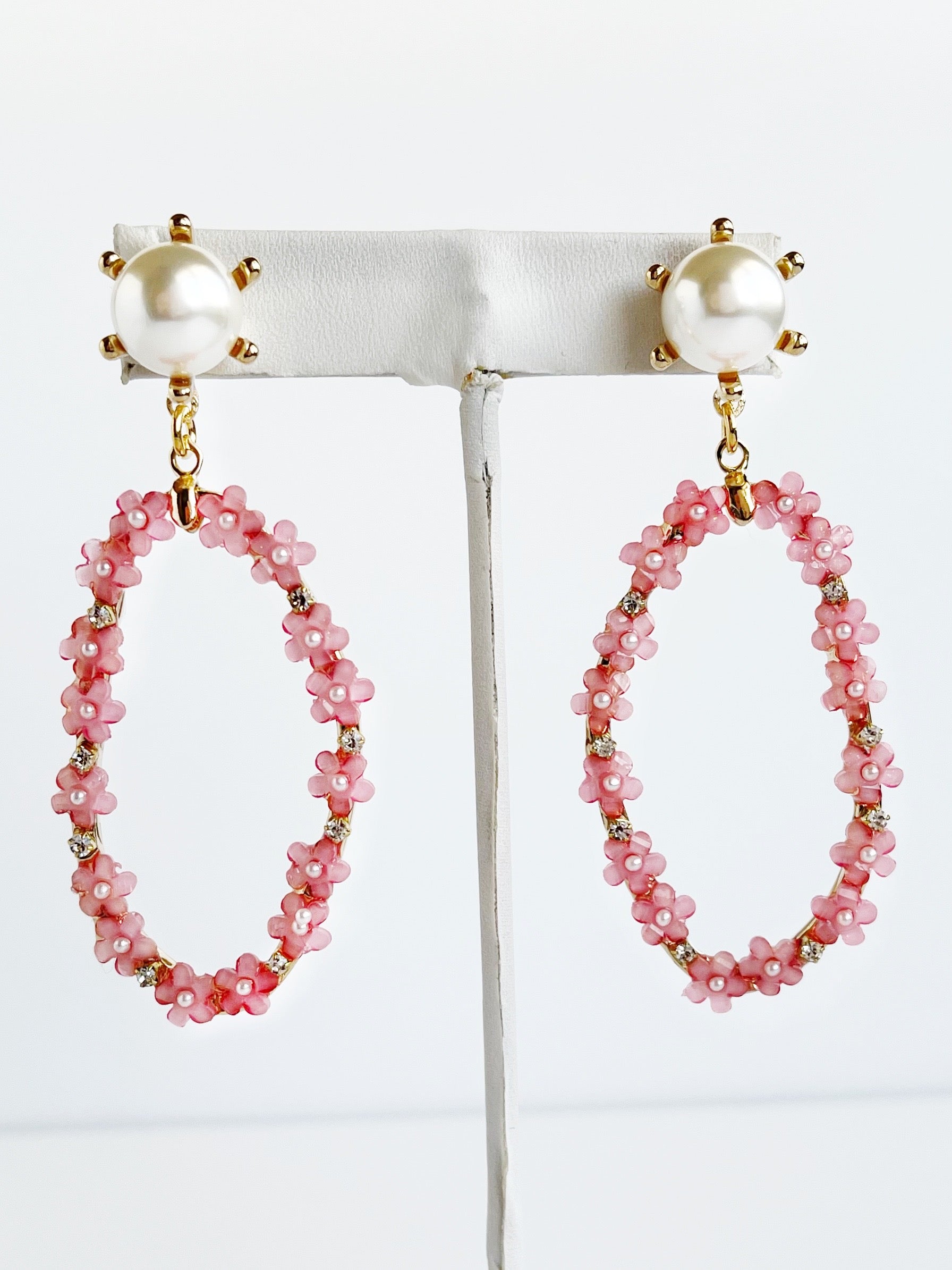 Pink glass flower and pearl long earrings on handing display